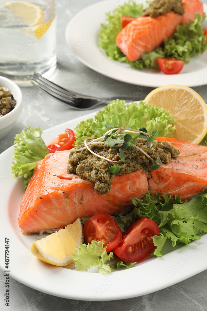 Tasty cooked salmon with pesto sauce and fresh salad served on grey table, closeup Tasty cooked salmon with pesto sauce and fresh salad served on grey table, closeup