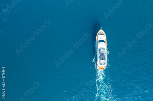 White seafoam trail left by luxury yacht sailing in Adriatic sea. Bright and warm sunlight illuminating calm ripple sea water. Aerial view