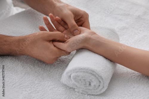 Woman receiving hand massage on soft towel, closeup