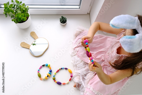 Beautiful smiling little child is wearing Easter bunny ears and holding a color wreaths  photo