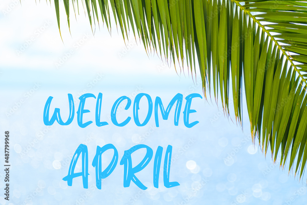 Welcome April message written in elegant font on the background with palm leaf and blue sea. Holiday concept and advertising of tour agency. 