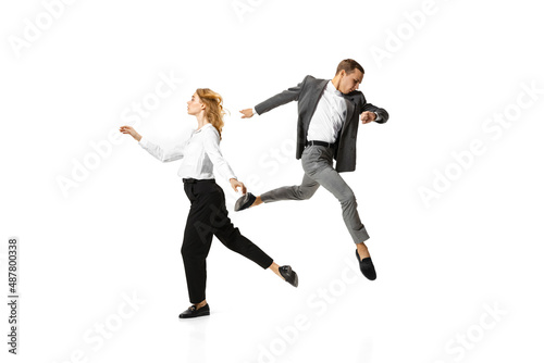 Two stylish office workers in business suits in action isolated on white background. Art, beauty, fashion and business concept