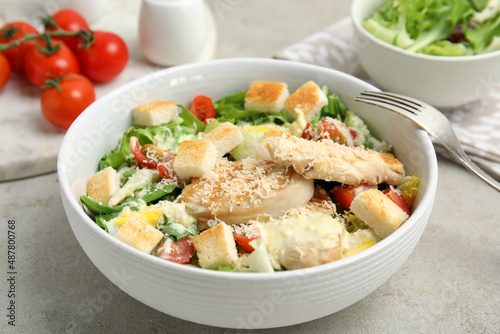 Delicious fresh Caesar salad in bowl on light grey table, closeup