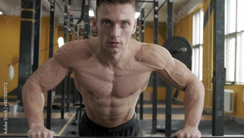 Muscular athletic man doing push-ups in the gym. Sport, weight lifting and health care concept
