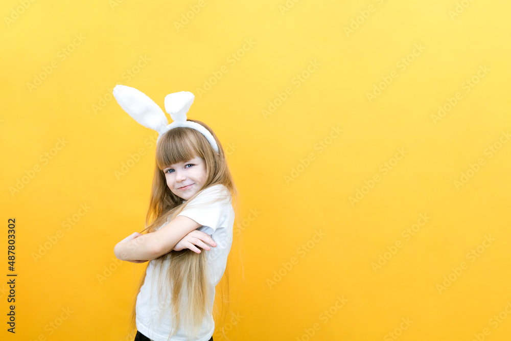 cheerful girl with rabbit ears on her head on a yellow background. Funny crazy happy child. Easter child. Preparation for the Easter holiday. promotional items. copy space for text cheerful girl with rabbit ears on her head on a yellow background. Funny crazy happy child. Easter child. Preparation for the Easter holiday. promotional items. copy space for text