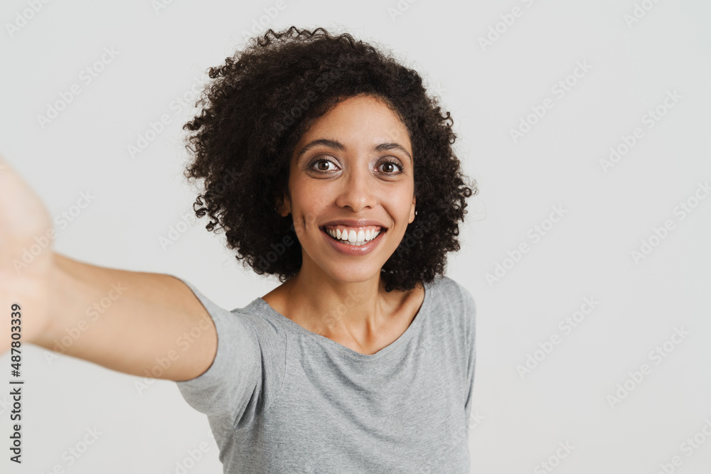 Young black woman with curly hair smiling while taking selfie photo Young black woman with curly hair smiling while taking selfie photo