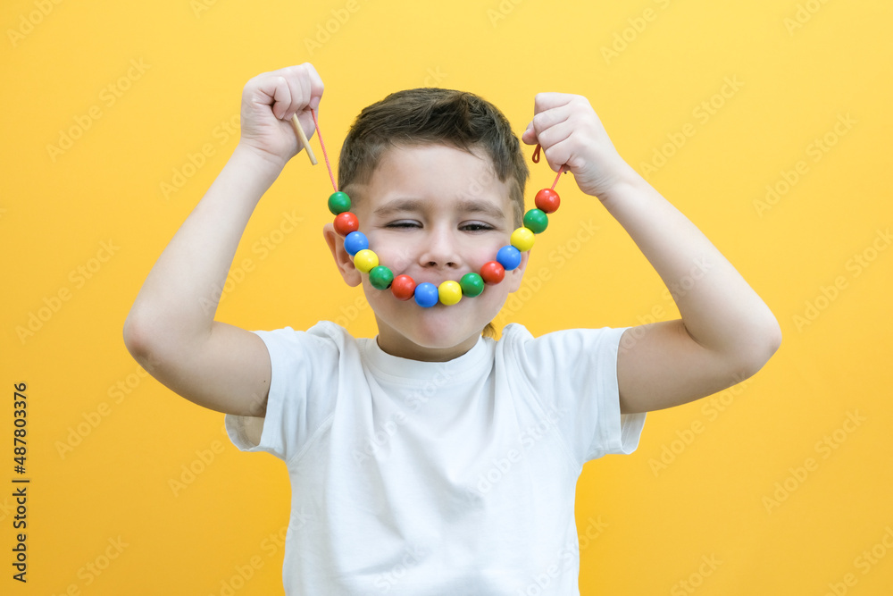 speech therapy, the development of fine motor skills. Toddler boy is stringing beads on a string. happy child speech therapy, the development of fine motor skills. Toddler boy is stringing beads on a string. happy child