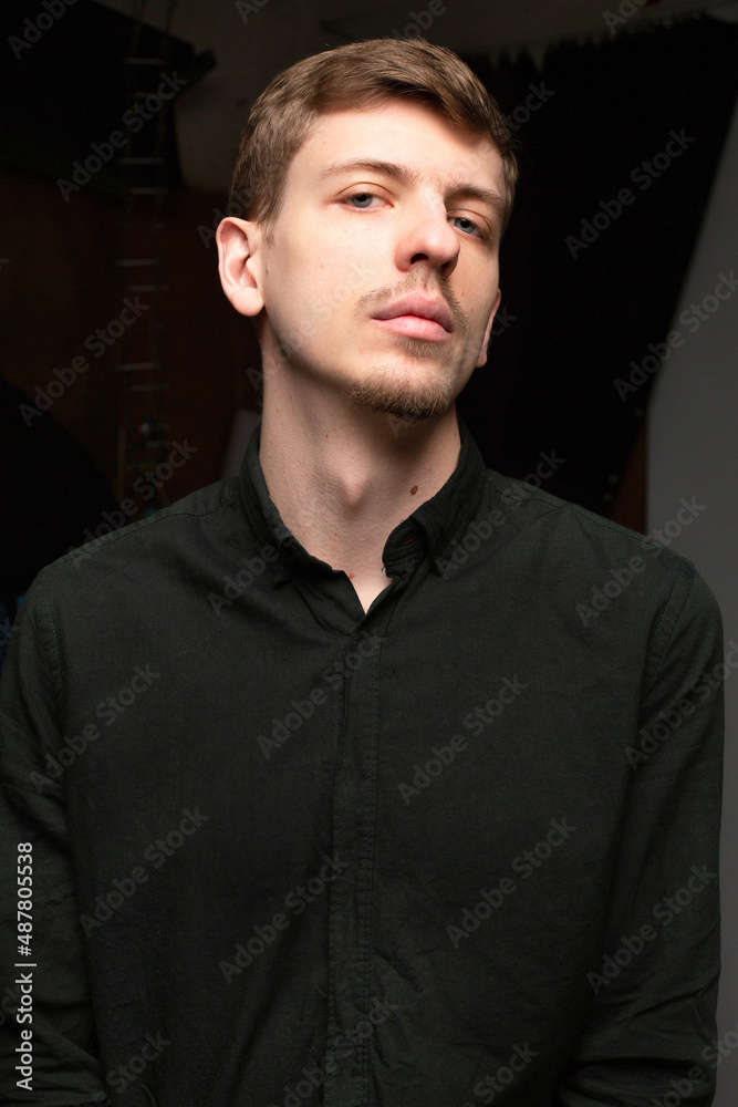 Portrait of young blond european man with short beard and mustache isolated on dark grey in black shirt Portrait of young blond european man with short beard and mustache isolated on dark grey in black shirt