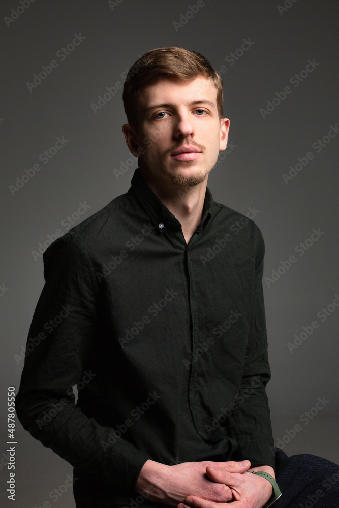 Young blond european man with short beard and mustache with clasped hands isolated on dark grey in black clothes Young blond european man with short beard and mustache with clasped hands isolated on dark grey in black clothes
