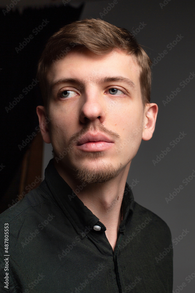 Young blond european man with short beard and mustache isolated on dark grey portrait Young blond european man with short beard and mustache isolated on dark grey portrait