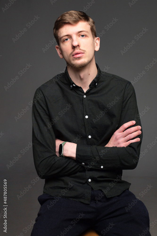 Young blond european man with short beard and mustache isolated on dark grey with folded arms Young blond european man with short beard and mustache isolated on dark grey with folded arms