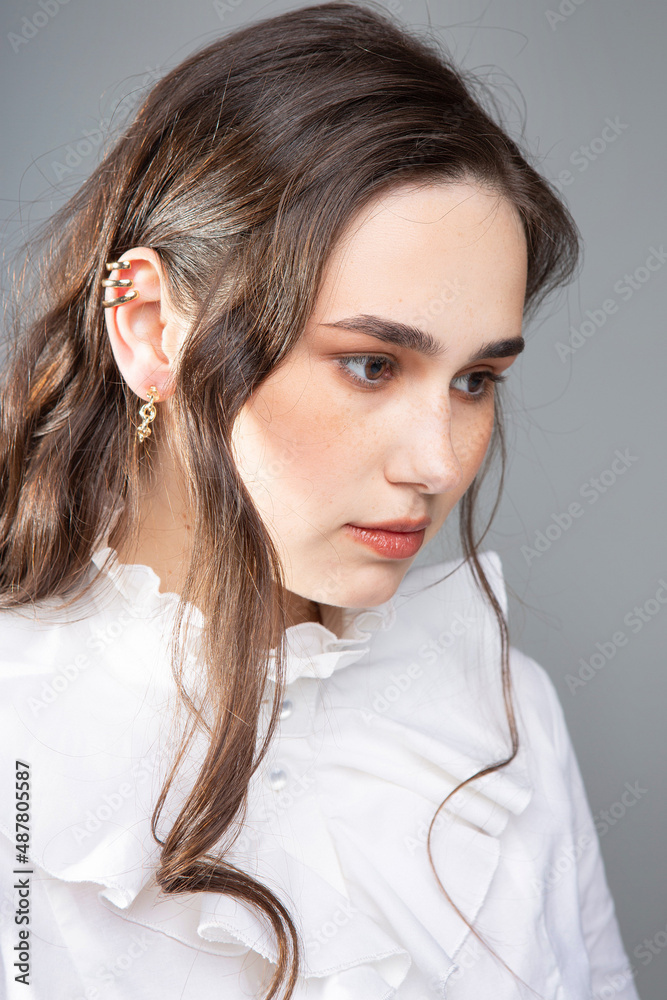 Portrait of young woman with long hair with dark brown eyes isolated on grey in white blouse Portrait of young woman with long hair with dark brown eyes isolated on grey in white blouse