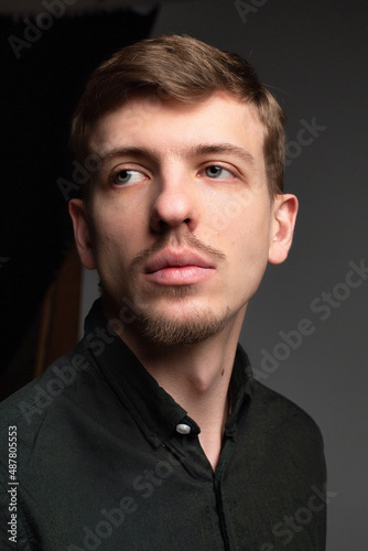 Young blond european man with short beard and mustache isolated on dark grey portrait