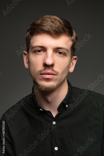 Young blond european man with short beard and mustache isolated on dark grey portrait in total black