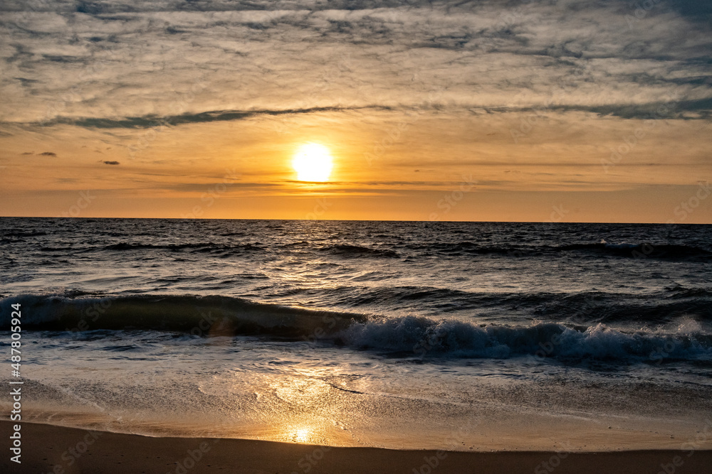 Obraz premium Waves breaking onto the shore at sunrise
