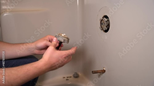 Close up 4k video of a man's hand pulling off part of the water faucet in a grey bathtub surround and analyzing it. Handy man, construction, DIY, working. Series.