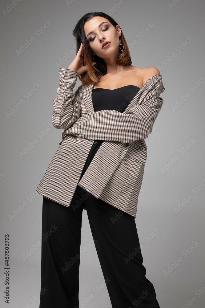 Slim young woman with short dark hair standing with closed eyes isolated on dark grey Slim young woman with short dark hair standing with closed eyes isolated on dark grey