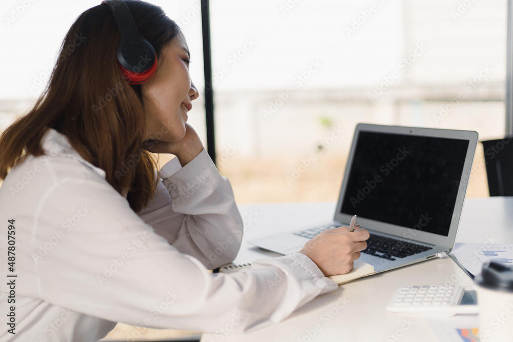 Woman wearing headphones working with laptop during online meeting. Internet work from home and online learning concepts. Woman wearing headphones working with laptop during online meeting. Internet work from home and online learning concepts.
