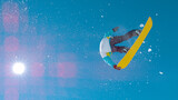 BOTTOM UP: Fearless male snowboarder soars up into sky and does a grab trick.