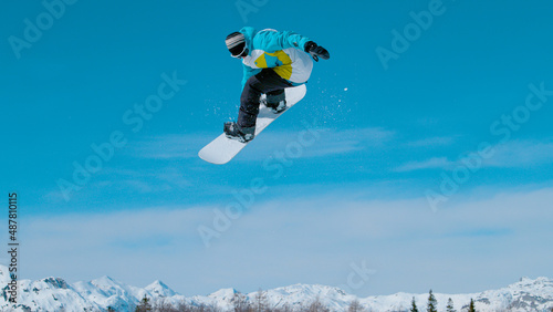 CLOSE UP: Male tourist doing a 360 grab while exploring the ski resort fun park.