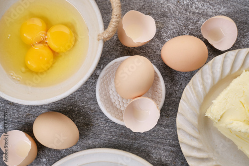 Butter, whole eggs, broken eggs, yolk on a bowl on the table