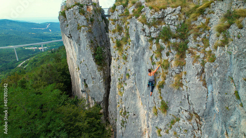 Fotografie, Obraz COPY SPACE: Drone view of a female rock climber ascending up a challenging cliff