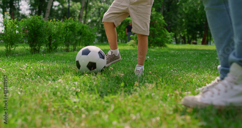 Unknown boy legs making soccer exercise closeup. Son training football with dad.
