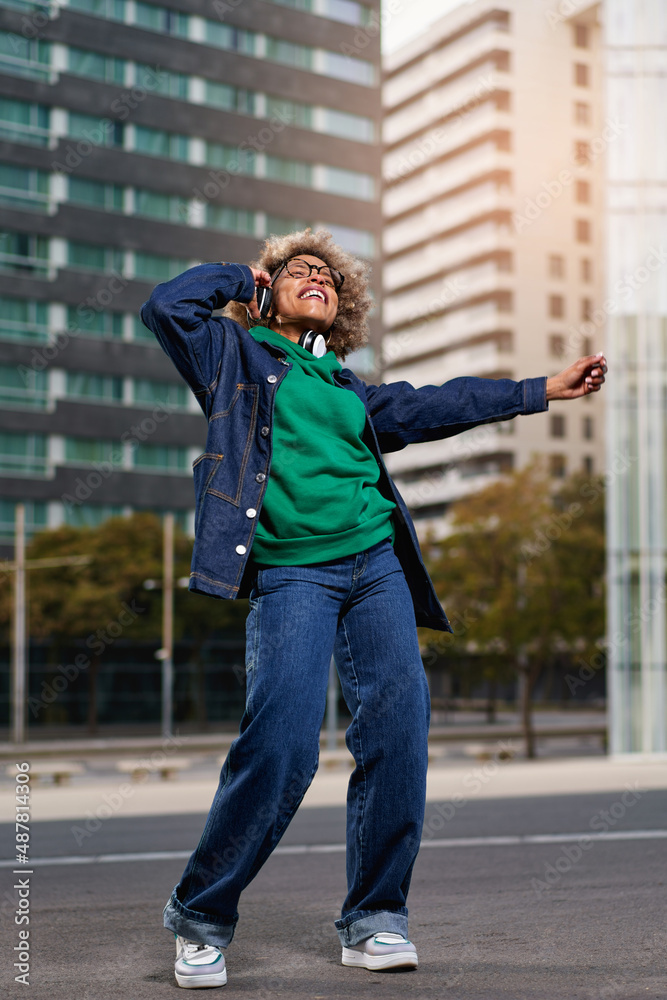 Portrait of young attractive black girl in urban background hearing music with headphones