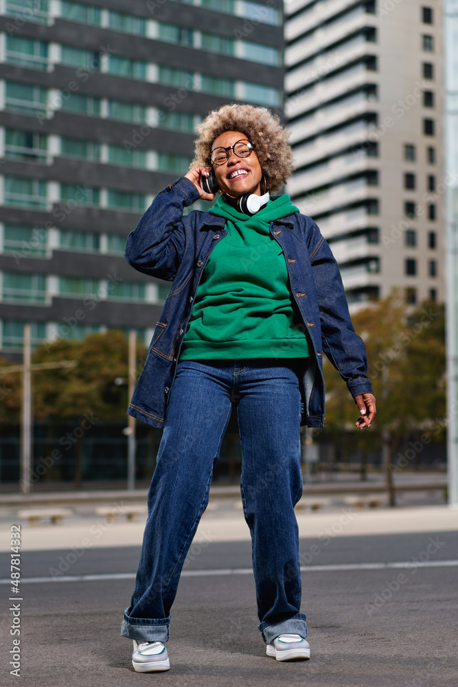 Portrait of young attractive black girl in urban background hearing music with headphones