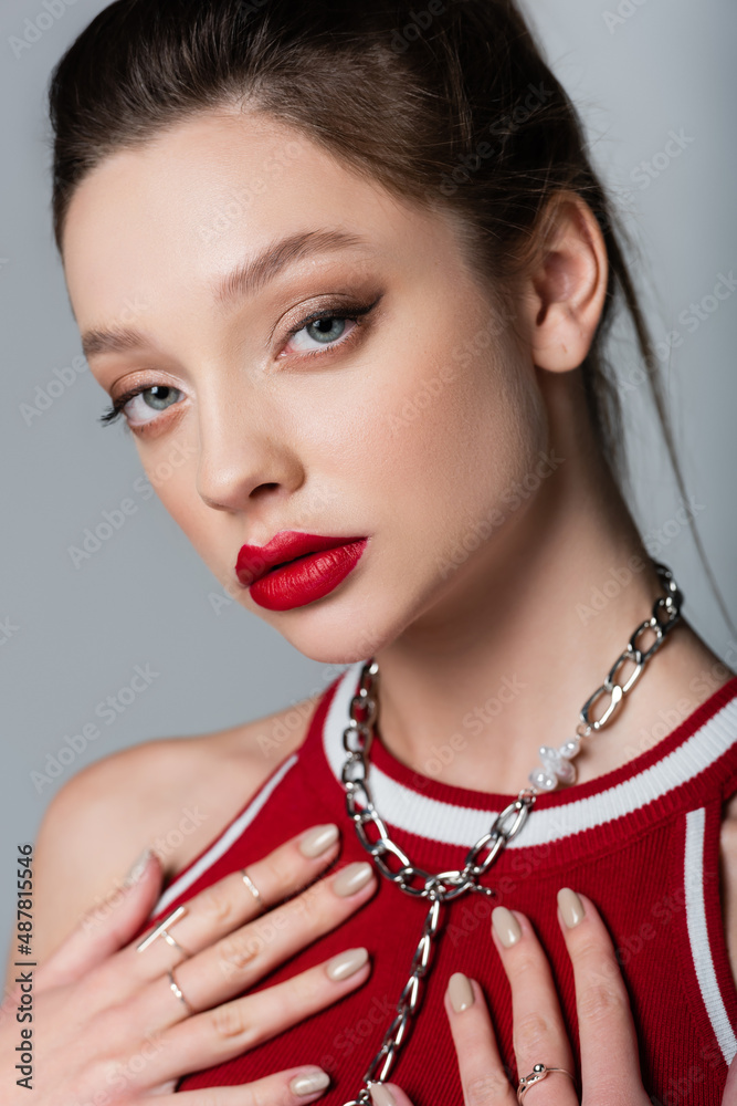 young woman with red lips and necklace chain isolated on grey.