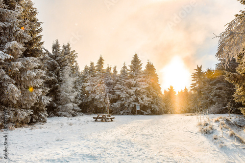 Winter landscape in the Polish mountains of the Sudetes, a crossroads on a walking trail, the sun's rays break through a thick layer of clouds on a winter afternoon. © Castigatio