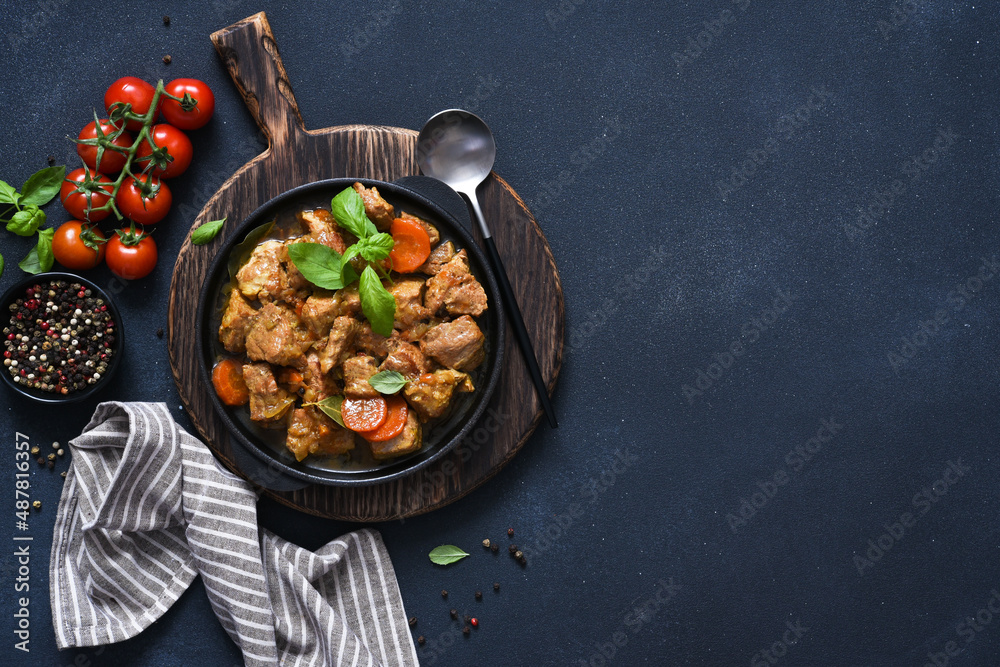 Stew with spices, tomatoes and carrots on a concrete cheno background.