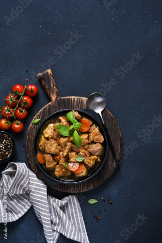 Stew with spices, tomatoes and carrots on a concrete cheno background. photo