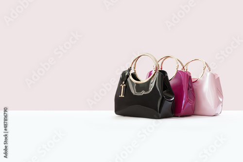 Beautiful black, pink leather female fashion bag isolated on light pink background, perspective view
