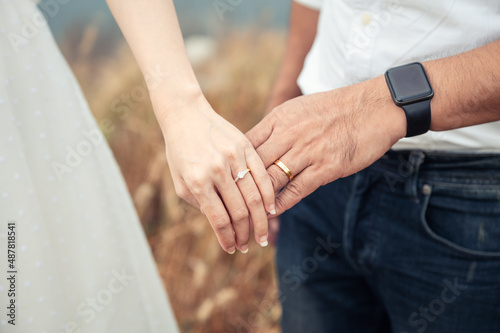 Bride and groom standing holding hands with wedding ring in the forest at pre wedding day. Wedding dress, Married couple