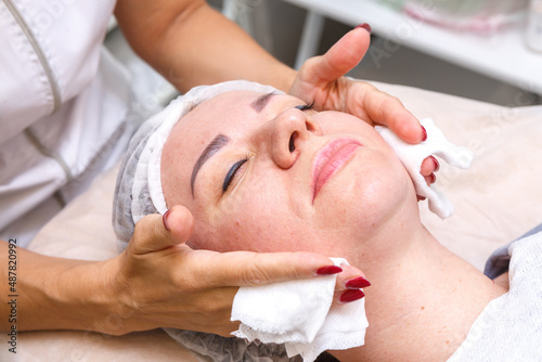 A cosmetologist performs spa treatments with the face of a young pretty woman.