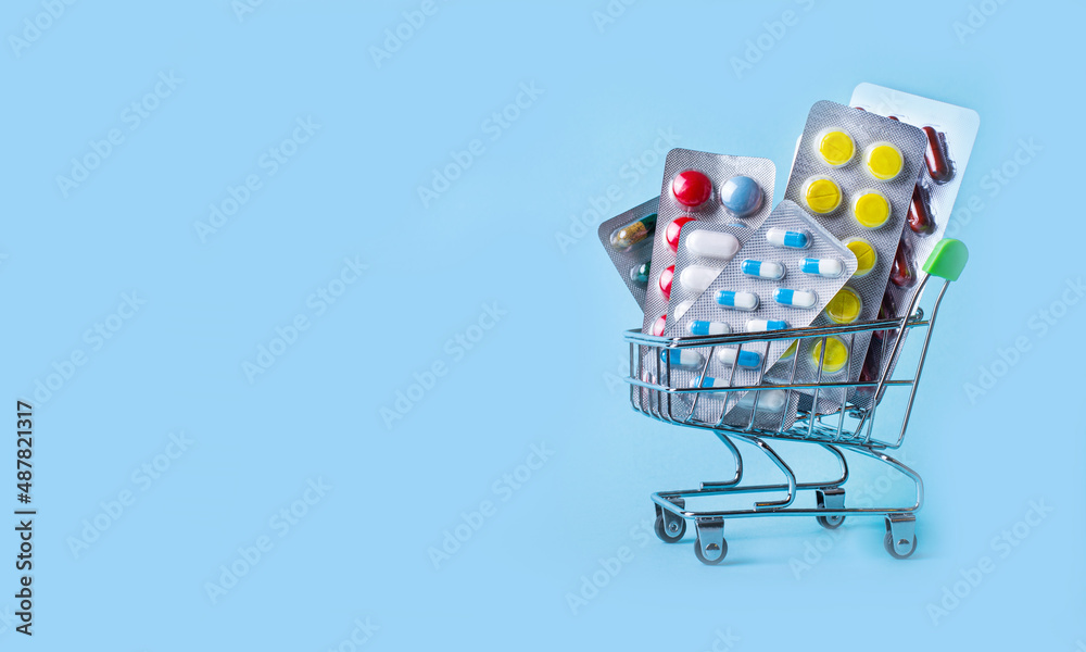 On a light blue background, a shopping trolley with pills. Medical concept. Copy space On a light blue background, a shopping trolley with pills. Medical concept. Copy space
