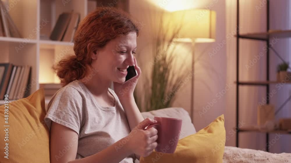 Phone call. Mobile communication. Gadget leisure. Joyful millennial woman talking on cellphone relaxing with coffee on couch at cozy home living room. Phone call. Mobile communication. Gadget leisure. Joyful millennial woman talking on cellphone relaxing with coffee on couch at cozy home living room.