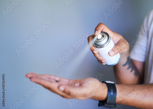 A side view of a man spraying hand sanitiser into his palm