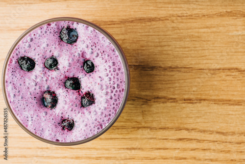 Top down view of blueberry smoothie on wooden board with copy space