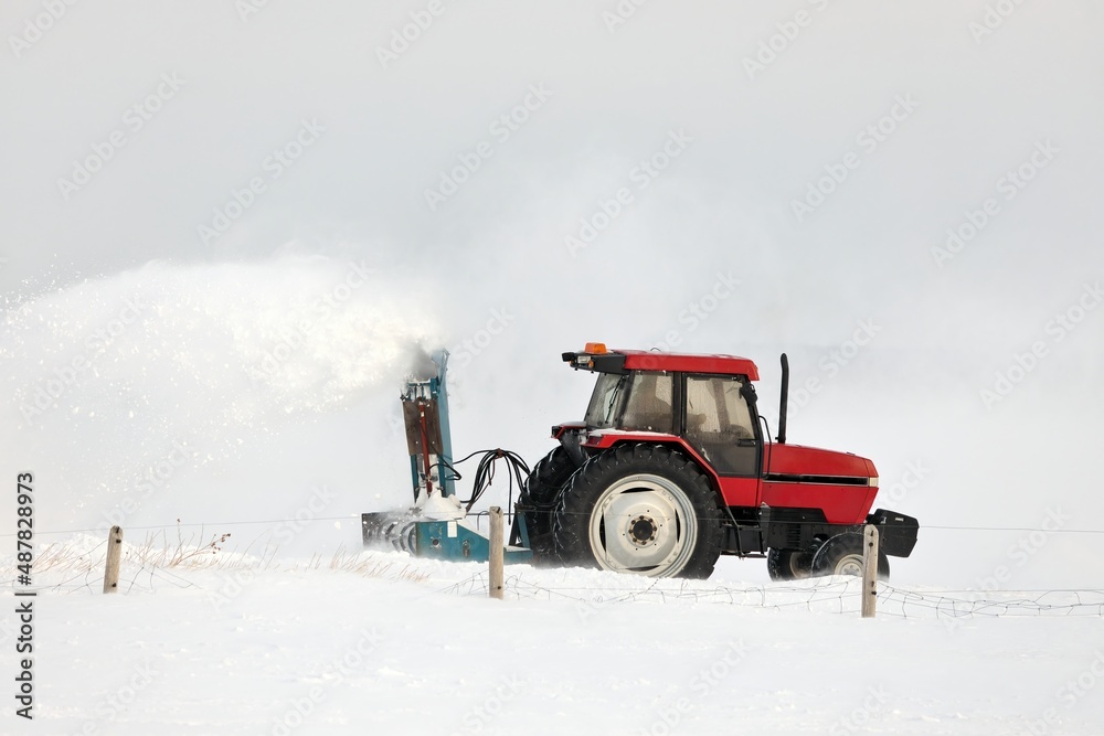Red Tractor Snow Blowing a Driveway in a Rural Setting Red Tractor Snow Blowing a Driveway in a Rural Setting