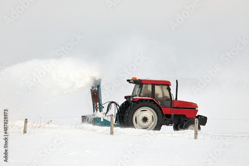 Red Tractor Snow Blowing a Driveway in a Rural Setting