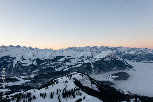 Amazing sunrise with red sky and a beautiful landscape in the wonderful region in Switzerland called Mythenregion. Beautiful mountain called Mythen and an epic sea of fog in the background.