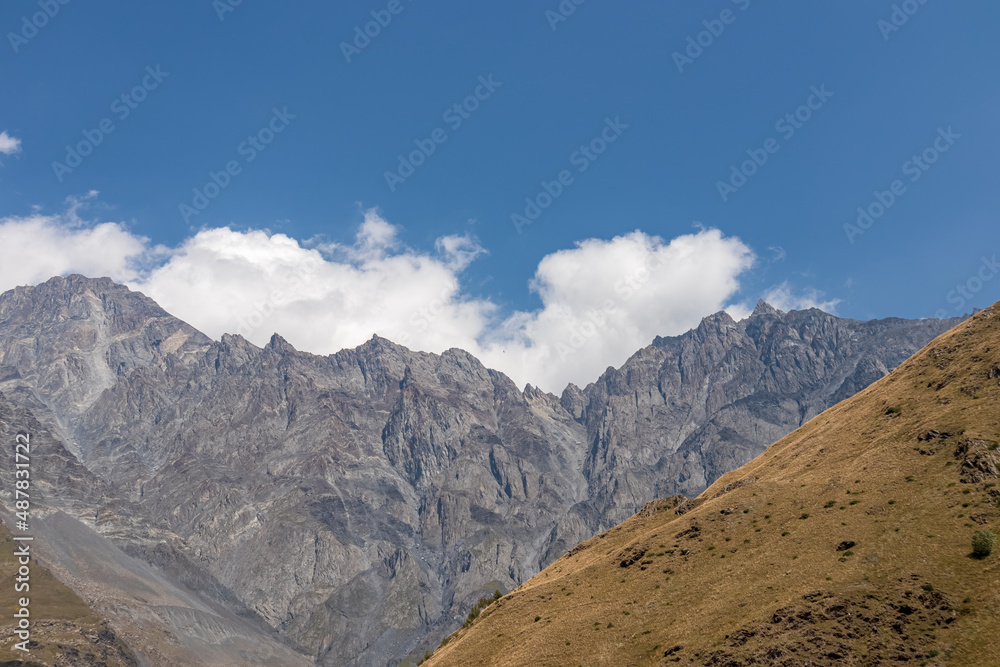 A panoramic view on the Kuro ridges in the Greater Caucasus Mountains in Georgia. There high slopes are barren and stony, lush pastures below.Clear and bright day.Khokh range. Stepantsminda.Adventure