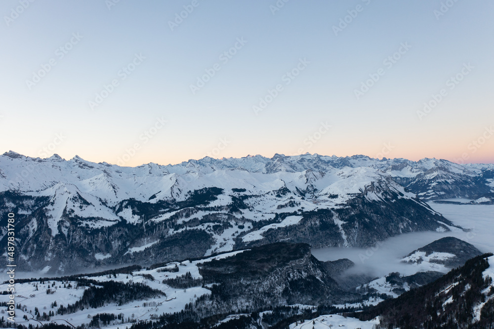 Obraz premium Amazing sunrise with red sky and a beautiful landscape in the wonderful region in Switzerland called Mythenregion. Beautiful mountain called Mythen and an epic sea of fog in the background.