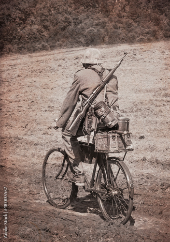 German soldier riding a bike. Photo of reconstruction of event taking place in time of World War II.