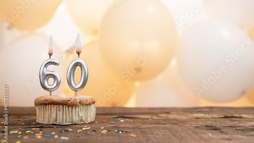 Happy birthday card with candle number 60 in a cupcake against the background of balloons. Copy space happy birthday for sixty years old