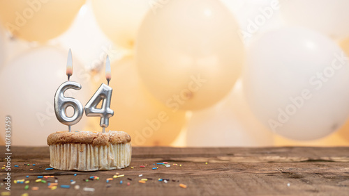 Happy birthday card with candle number 64 in a cupcake against the background of balloons. Copy space happy birthday for sixty four years old photo