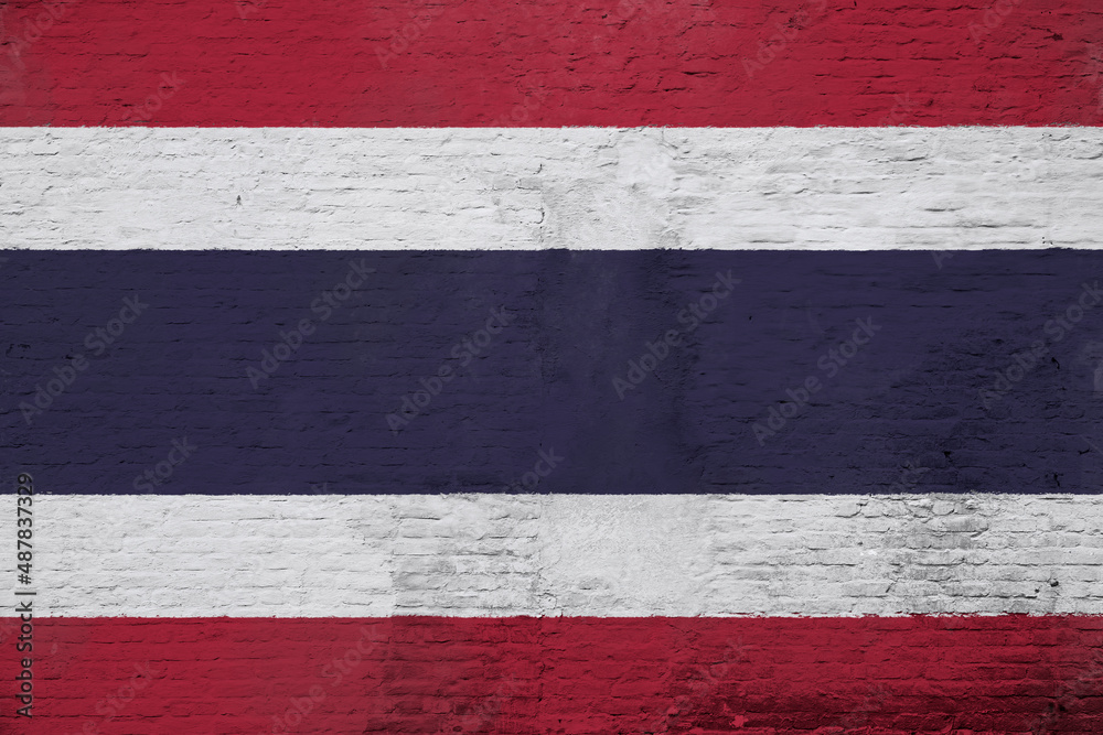 Full frame photo of a weathered flag of Thailand painted on a plastered brick wall.