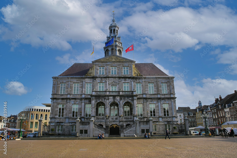 Maastricht, Netherlands - February 13. 2022: View over market square on town hall building from 17th century against blue morning winter sky (focus on front facade of big building)